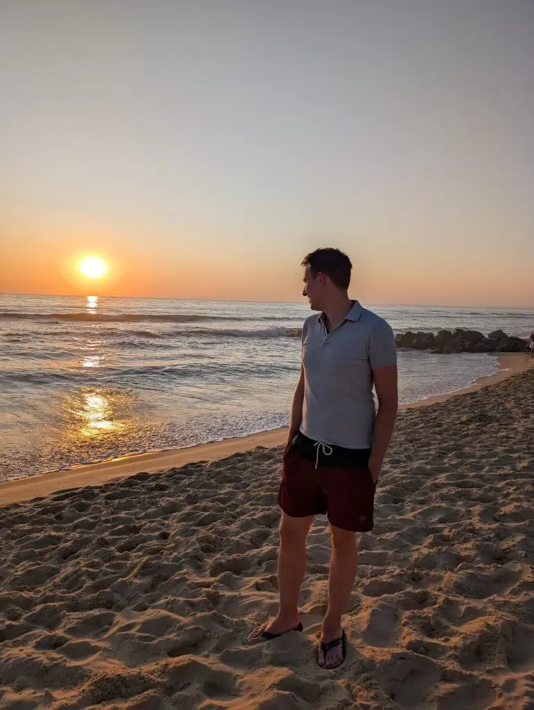 Sonnenuntergang am Strand, eine Person blickt aufs Meer