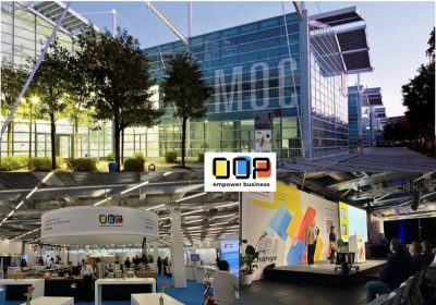 Eine Übersicht verschiedener Perspektiven auf die OOP2026. Oben sieht man den Veranstaltungsort, das Münchner MOC, von außen. Unten links ein Blick in den Vorraum zur Konferenz, wo auch die Aussteller-Bereiche sind. Und rechts ein Blick auf die Bühne der Eröffnungsansprache. In der Mitte das Logo der OOP mit dem Schridtzug "empower business".